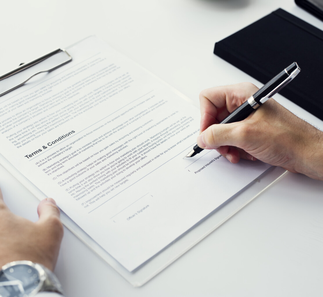 Closeup of hand signing paper workspace